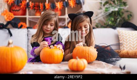 Bezaubernde Mädchen, die zu Hause eine halloween-Party veranstalten und Kürbis malen Stockfoto