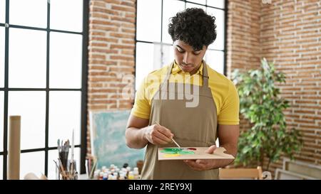 Junger lateinischer Künstler, der im Kunststudio Farben auf Farbpalette mischt Stockfoto