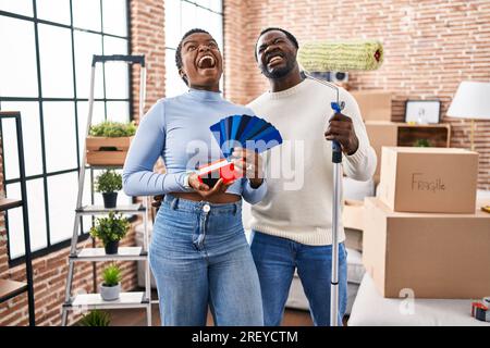 Ein junges afroamerikanisches Paar zieht in ein neues Haus und wählt Wände, die wütend und verrückt sind, frustriert und wütend, schreiend mit Wut, die aufblickt Stockfoto