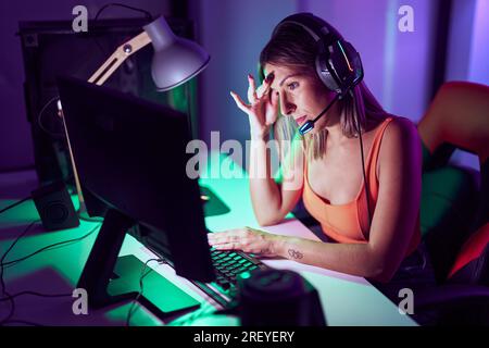 Junge schöne hispanische Frau Streamer betonte mit Computer im Spielzimmer Stockfoto