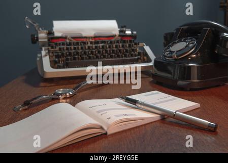 Scheckbuch mit einer leeren Seite für Details auf Französisch. Retro-Konzept mit altem Telefon, Tintenstift und Schreibmaschine. In Farbe Stockfoto