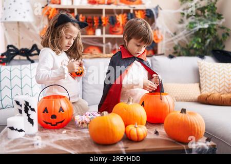 Ein bezaubernder Junge und ein bezauberndes Mädchen, die zu Hause halloween feiern Stockfoto