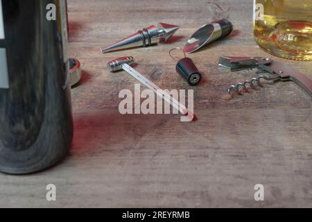 Wein-Set aus Zubehör. Zusätzliche Stopfen, Öffnungen, Korkenzieher und Thermometer. Auf der Texturtabelle. Nahaufnahme. Stockfoto