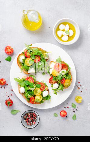 Bruschetta mit Kirschtomaten, Mini Mozzarella Käse und Pesto Sauce, Caprese Toasts, leckerer Snack Stockfoto