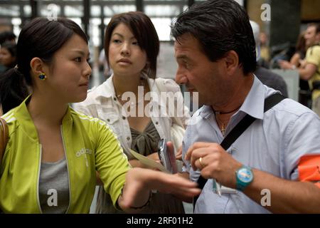 Mitarbeiter des Bahnhofs Trenitalia helfen den Fahrgästen am belebten Mailänder Hauptbahnhof, dem italienischen nationalen Eisenbahnsystem, 2005 Stockfoto