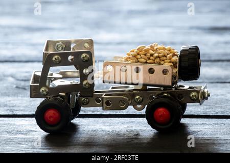Frachttransport von Getreide auf einem Schreibmaschinenwagen für Kinder, hergestellt aus einem Metallkonstruktor auf einer Holzplatte, Logistik, Transport von Getreide Stockfoto