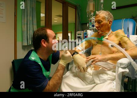 Eine Krankenschwester auf der Intensivstation erklärt einem älteren Patienten in einem NHS-Krankenhaus in Südwestengland die Verfahren. Stockfoto