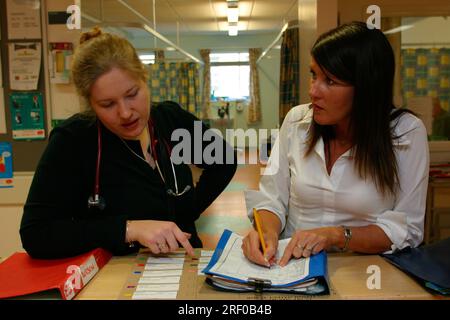 Zwei medizinische Fachkräfte diskutieren Patienteninformationen in einem Krankenhaus. Stockfoto