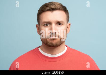 Porträt eines traurigen, frustrierten Mannes mittleren Alters mit Purpenlippen in Schwierigkeiten auf blauem Hintergrund. Stockfoto