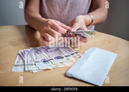 Frau, die Geld zählt, Sterling, Ersparnisse, Rechnungen bezahlen, Lebenshaltungskosten, UK Stockfoto