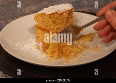 Eine Person isst Zitronen-victoria-Sandwichkuchen mit einer Gabel. Stockfoto