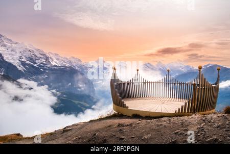 Aussichtspunkt auf dem Gipfel des Mannlichen Berges bei Lauterbrunnen und Grindelwald, Schweiz, bei Sonnenuntergang. Schneebedeckte Gipfel der Schweizer Alpen in niedrigen Wolken Stockfoto