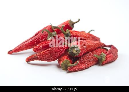 Ein Haufen teilweise getrockneter würziger roter Paprika auf einem sauberen weißen Hintergrund. Stockfoto