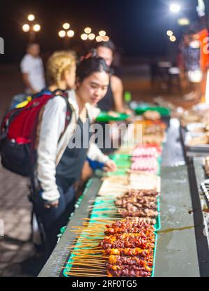 Dumaguete, Negros Island, Philippinen-Januar 29 2023: Jeden Abend, in der Nähe des Meeres, eine große Auswahl an spießigen, fleischhaltigen Snacks werden zubereitet und vertrieben Stockfoto