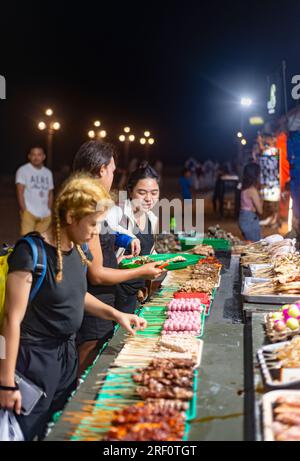 Dumaguete, Negros Island, Philippinen-Januar 29 2023: Jeden Abend, in der Nähe des Meeres, eine große Auswahl an spießigen, fleischhaltigen Snacks werden zubereitet und vertrieben Stockfoto