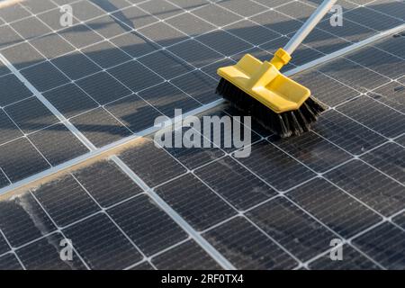 Reinigen von Solarmodulen. Erneuerbare Energie. Waschen von Solarmodulen von Staub und Schmutz auf dem Dach mit Wasser. Effizienz von Solarmodulen. Stockfoto