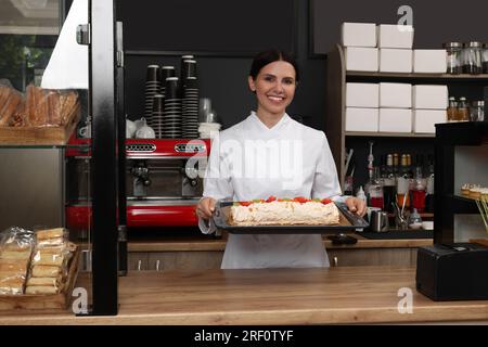 Happy Baker präsentiert köstlichen Kuchen mit Erdbeeren im Café Stockfoto