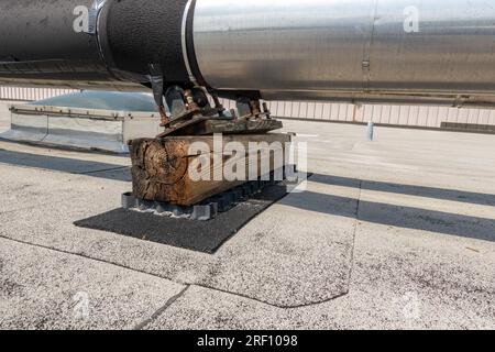 Dachmontierte industrielle isolierte HLK-Rohre auf grauem Dach und Holzstützen. Stockfoto