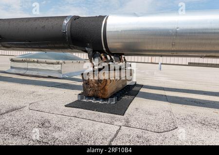 Dachmontierte industrielle isolierte HLK-Rohre auf grauem Dach und Holzstützen. Stockfoto