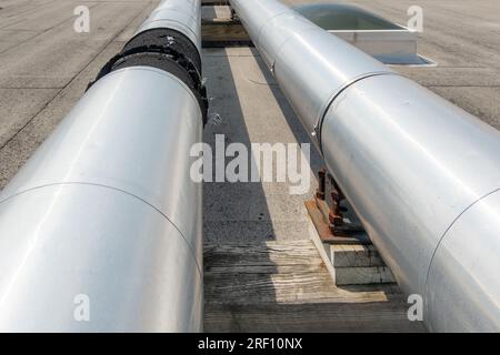 Dachmontierte industrielle isolierte HLK-Rohre auf grauem Dach und Holzstützen. Stockfoto