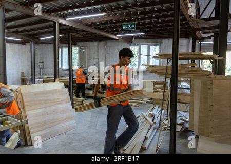 Antakya, Türkei. 18. Juli 2023. Im Rahmen des Projekts „Yuva“ (Nest) bauen Freiwillige im Bezirk Samandag ökologische Holzhäuser, die Unternehmen oder Privatpersonen über eine Partnerorganisation an Erdbebenopfer spenden können. Das Projekt „Yuva“ (Nest) beschäftigt 15 Frauen und 15 Männer aus der Region, die selbst vom Erdbeben betroffen sind. Notunterkünfte in der Hitze und den Schutt - sechs Monate nach den Erdbeben im Südosten der Türkei am 6. Februar leiden die Menschen noch immer unter den Folgen. Kredit: Bradley Secker/dpa/Alamy Live News Stockfoto