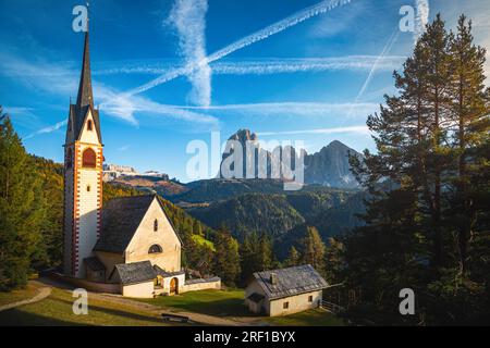 Eine der malerischsten Gebirgskirchen in den Dolomiten. St. Jakob Kirche im Wald und wunderschöne hohe Berge im Hintergrund, Ortisei, Gard Stockfoto