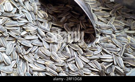 Ein Haufen gestreifter Sonnenblumenkerne, ein Imbiss, mit einer Stahlschaufel, der auf dem traditionellen asiatischen Markt verkauft wird. Die Samen der Sonnenblume (Helianthus annuus) Stockfoto