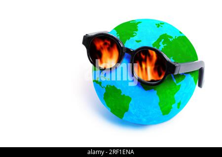 Miniaturkugel mit stilvoller Sonnenbrille, die Flammenzungen in den Linsen reflektiert und die dringenden Probleme der globalen Erwärmung und des Waldes symbolisiert Stockfoto