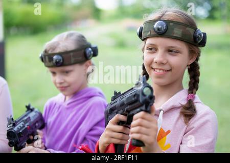 Belarus, Dorf Yagodnaya, 27. Mai 2021. Kinderurlaub. Mädchen mit Laserwaffen spielen Laser-Tag. Stockfoto