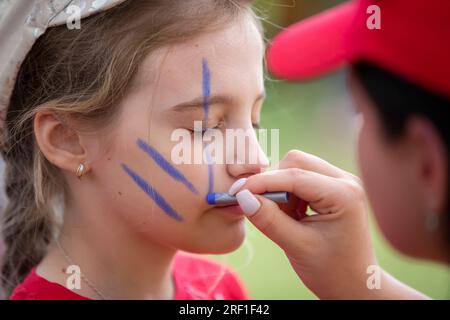 27. Mai, 2021. Belarus. Dorf Yagodnaya. Kinderurlaub. Make-up-Künstler zeichnet Gesichtsmalerei auf das Gesicht eines Kindes. Stockfoto