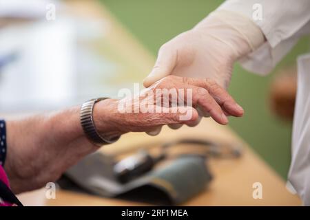 Die Hand des Arztes hält die Hand des alten Mannes. Nahaufnahme eines Arztes und zitternde Hand einer behinderten älteren Frau. Das menschliche Alternskonzept. Stockfoto
