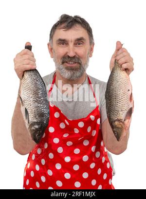 Reifer Fischhändler in roter Schürze, der große Süßwasserfische hält und auf weißem Hintergrund auf die Kamera schaut Stockfoto