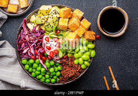 Vegane buddha-Schüssel mit roter Quinoa, gebratenem Tofu, Avocado, Edamambohnen, grünen Erbsen, Rettich, Kohl, Granatäpfel und Sesamsamen mit Sojasauce. Heilen Stockfoto