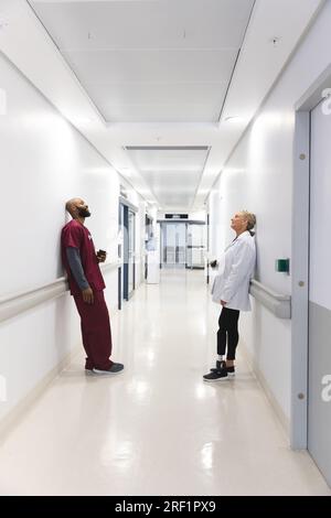 Verschiedene männliche und weibliche Ärzte halten Kaffee zum Mitnehmen im Flur im Krankenhaus Stockfoto