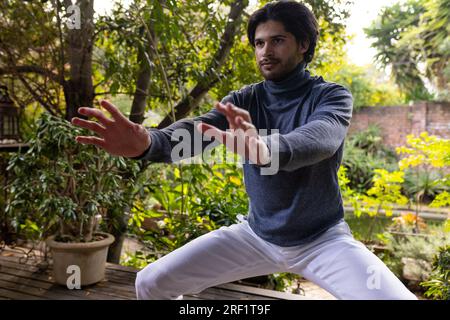 Fokussierter indischer Mann, der Yoga auf der sonnigen Terrasse praktiziert Stockfoto