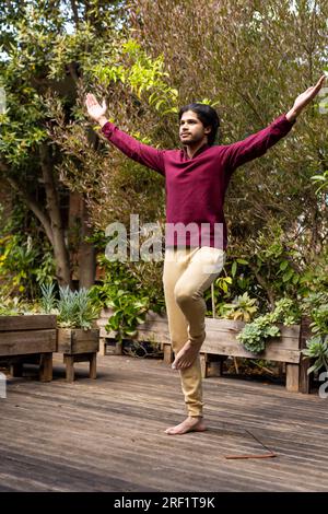 Fokussierter indischer Mann, der Yoga auf der sonnigen Terrasse praktiziert Stockfoto