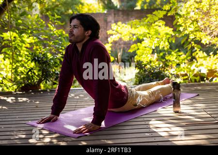 Fokussierter indischer Mann, der Yoga auf der sonnigen Terrasse praktiziert Stockfoto