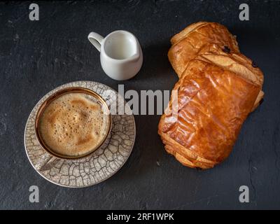 tasse Kaffee und Mini-Milchbecher mit Gebäck beiseite, einfaches Frühstückskonzept Stockfoto