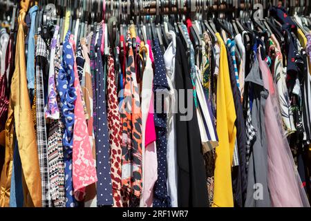 An Kleiderbügeln hängen verschiedene Sommerkleider aus preisgünstigen Stoffen. Verkauf von Sommerkleidung. Stockfoto