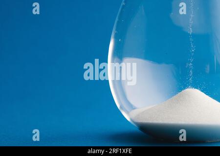 Nahaufnahme der Sanduhr mit weißem Sand und Kopierbereich auf blauem Hintergrund Stockfoto