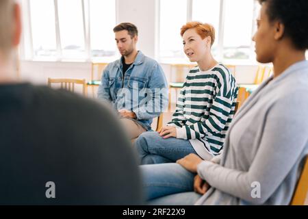 Selektivfokus der jungen Frau in der Gruppenpsychotherapiesitzung, die Patienten über psychische Probleme informiert. Weibliche, die über traumatische Erfahrungen spricht Stockfoto