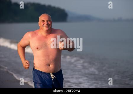 Ein alter Mann mit sportlicher Stärke joggt am Meer entlang. Der Mann geht zum Sport. Stockfoto