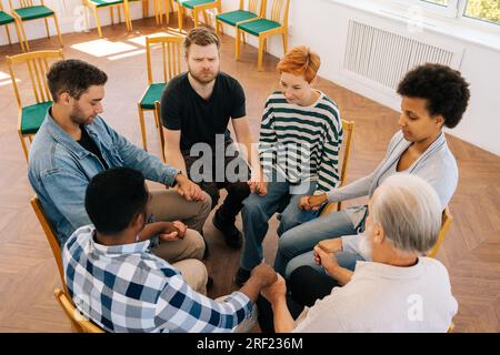Draufsicht von Menschen verschiedener Altersgruppen, die sich im Kreis an den Händen halten. Top-View-Gruppentherapie und Geschäftsleute im Team-Building zur Unterstützung Stockfoto