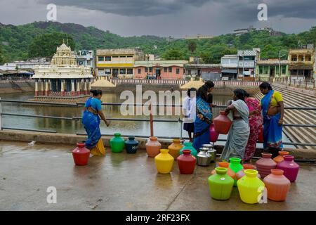 Frauen, die Trinkwasser aus dem kommunalen Wasserhahn in der Nähe des Saravana Poigai-Tanks am Fuße des Murugan Temple Hill in Thiruttani Tiruttani, Tamil, sammeln Stockfoto