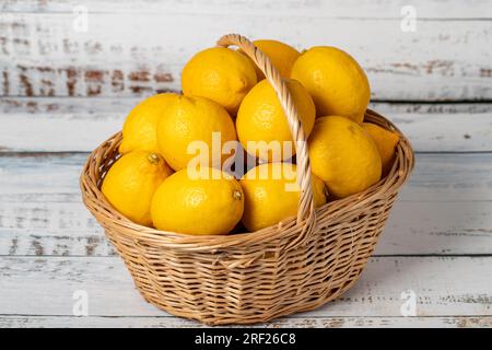 Frische Zitrone in einem Korb aus Korb aus Korb mit Holzhintergrund. Zitronenerntezeitkonzept. Gemüse für eine gesunde Ernährung Stockfoto