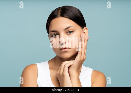 Nahaufnahme eines glücklichen Mädchengesichts mit natürlichem gekämmtem Haar, das gut gepflegte, reine, perfekte Haut berührt Stockfoto