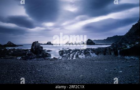 Panoramablick auf den bewölkten, stimmungsvollen Sonnenaufgang am Strand von Gueirua Stockfoto