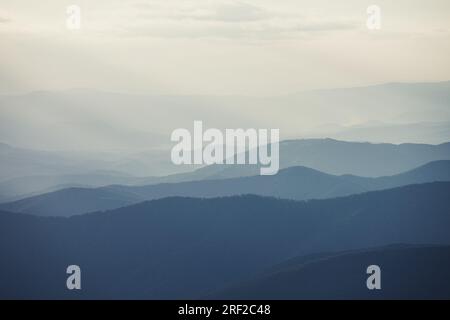 Bergkette mit sichtbaren Silhouetten durch den morgendlichen bunten Nebel Stockfoto