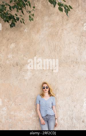 Junge Frau, die an die Wand lehnt Stockfoto