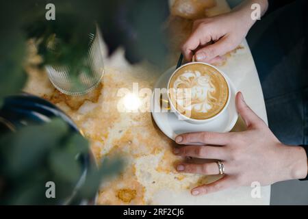 Weibliche Hände mit Ring halten eine Tasse Kaffee Stockfoto